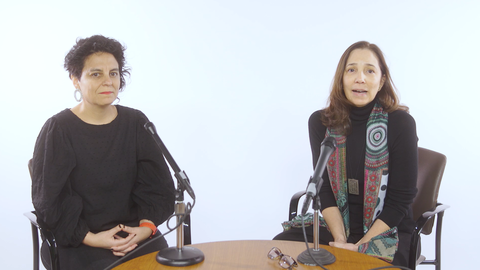 Alejandra Meneses and Paola Uccelli sitting on stools and recording a podcast
